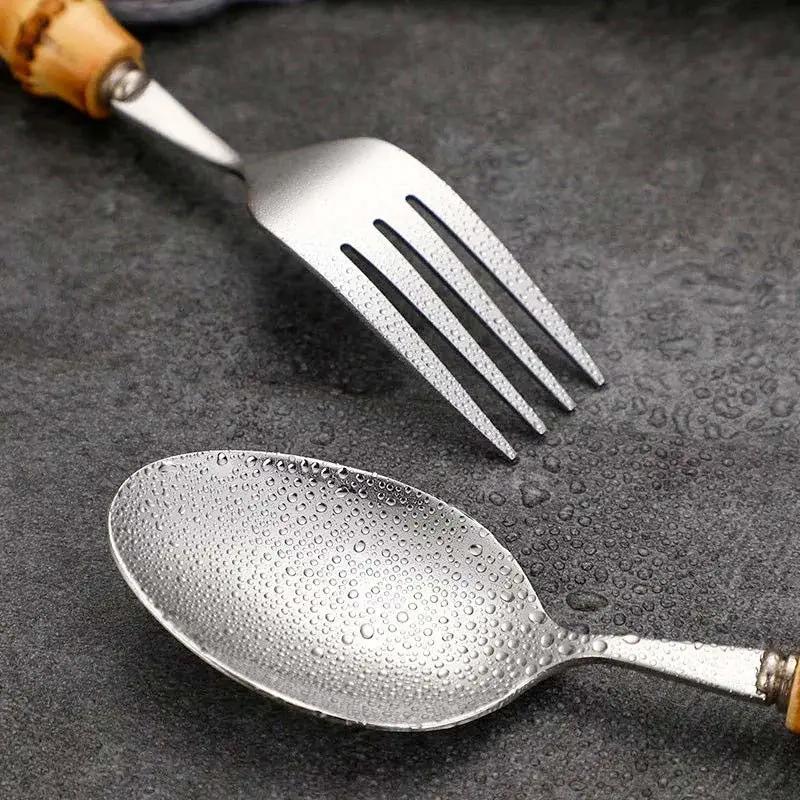 Stainless steel fork and spoon with water droplets on a dark textured surface
