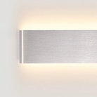 Wall light in brushed aluminium, wall-mounted with up and down LED glow on a white wall.