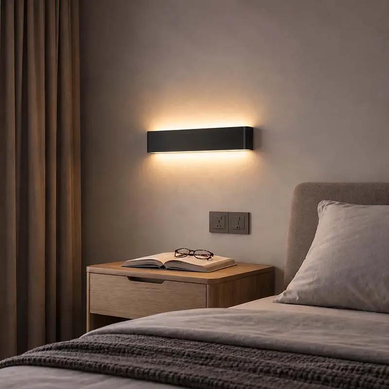 Minimalist LED Wall Light black aluminium up & down wall lamp in bedroom above bedside table.