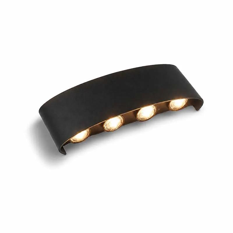 A modern curved wall light fixture with a matte black metal frame and four illuminated warm-white LED bulbs, shown against a plain white background.
