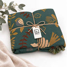 100% Cotton Reversible Throw Blanket, teal with birds and foliage, Nordic Essentials tag visible on folded throw
