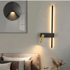 Wall lights: vertical LED strip with brass adjustable reading arm on a dark wall sconce above a bed in bedroom.