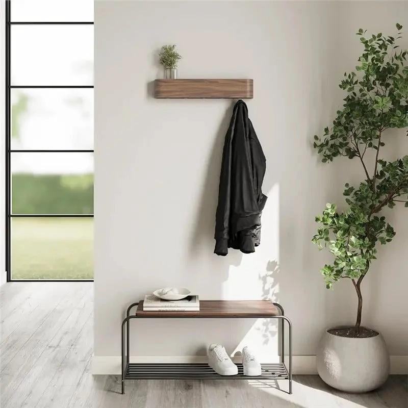 Wood and iron coat rack with hidden hooks and shelf mounted in a modern entryway beside a bench.