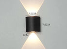 Modern Outdoor LED Wall Lamp, black cylindrical outdoor wall light mounted on a wall, emitting up and down warm light.