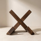 Wooden 'X' block on a beige surface with a neutral background
