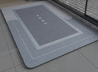 Blue gray non slip bath mat with 'HOME' text on a bathroom floor
