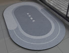 Blue gray non slip bath mat with 'HOME' text on a bathroom floor