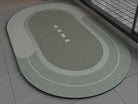 Green oval bathroom non slip rug with 'HOME' text on a bathroom floor